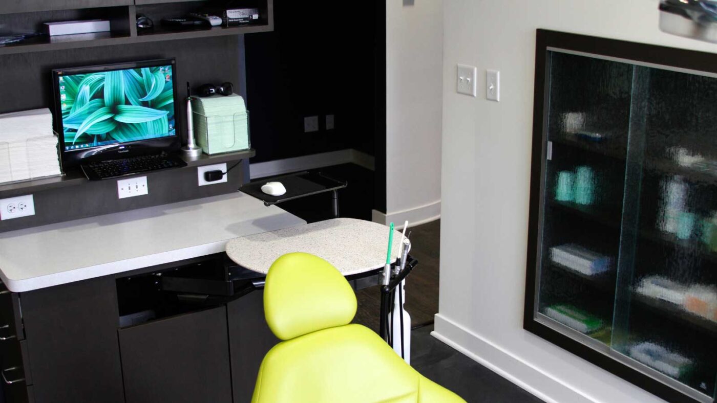 A modern dental office setup with a green chair and computer station