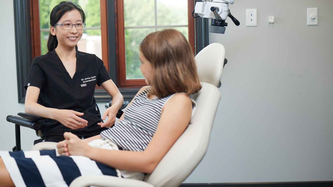 A caring endodontist consults with a young patient in a dental chair