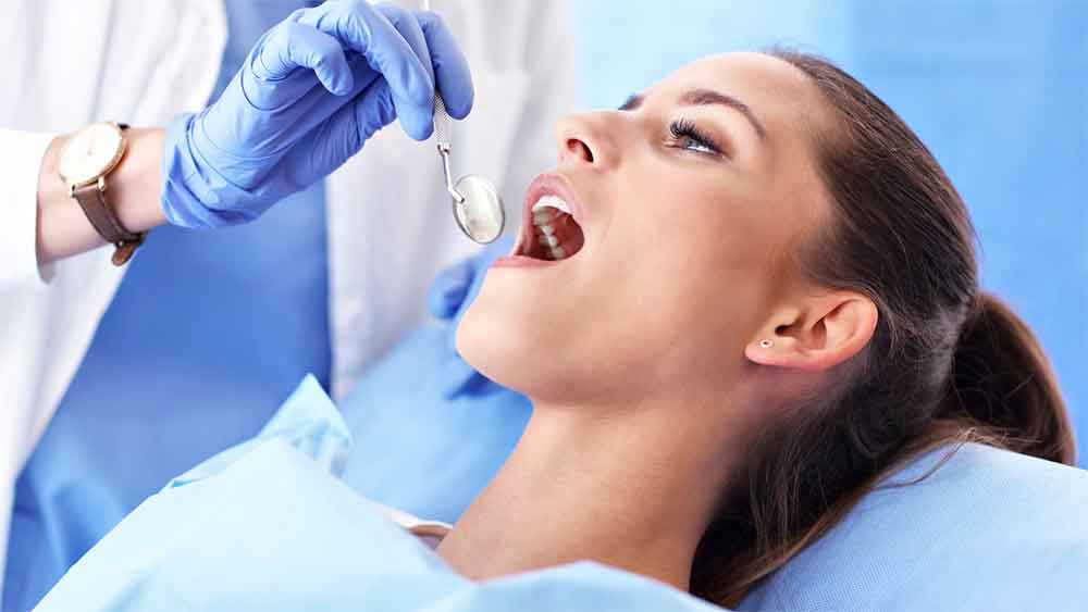 Dentist examining a patient's teeth with a dental mirror