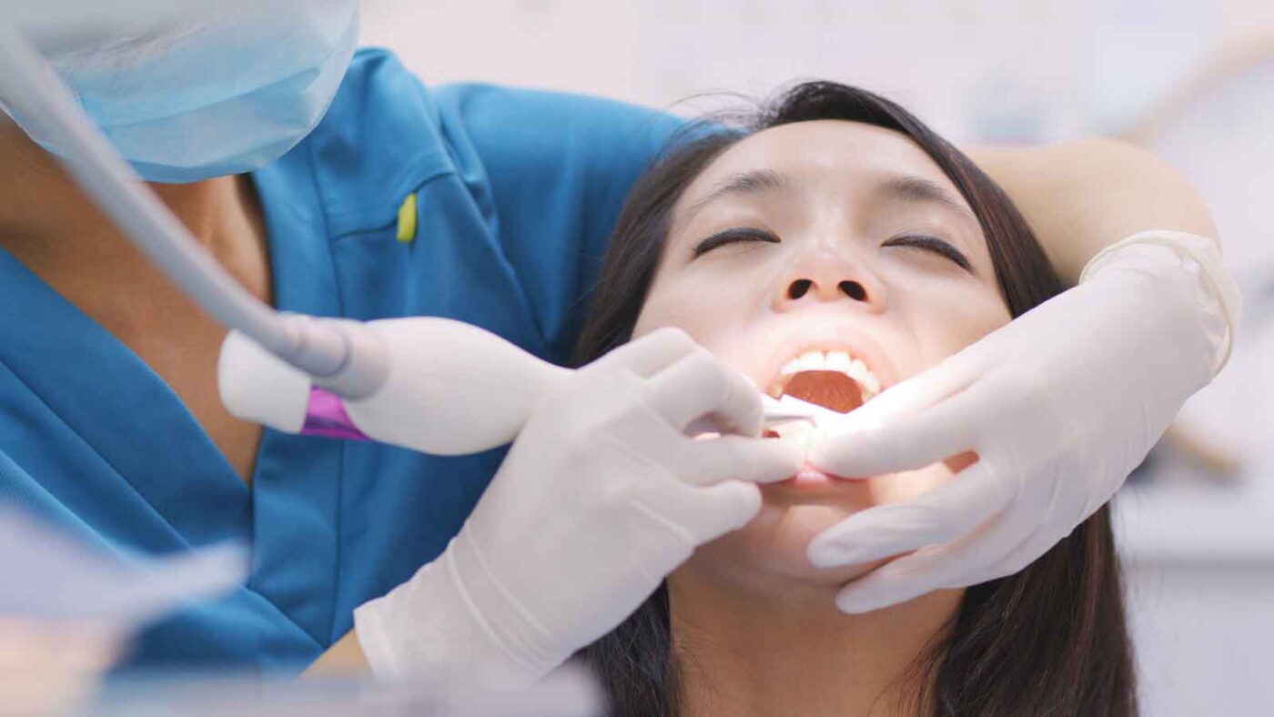 Dentist performing a dental procedure on a female patient.