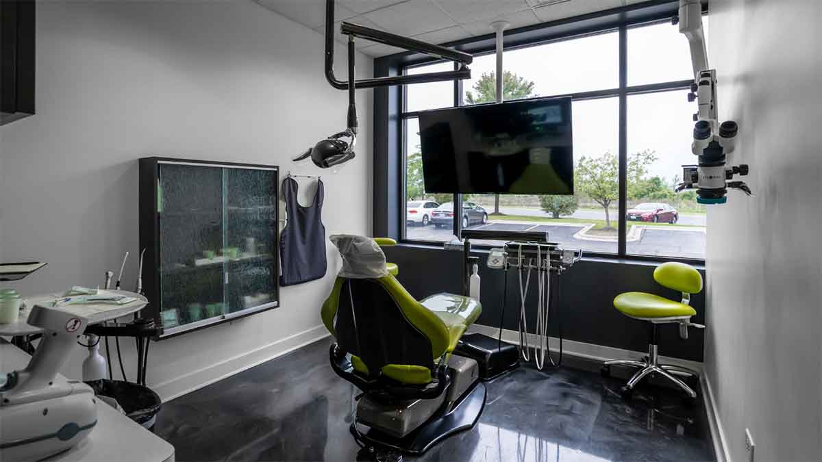  Modern dental exam room with a green chair and large window.