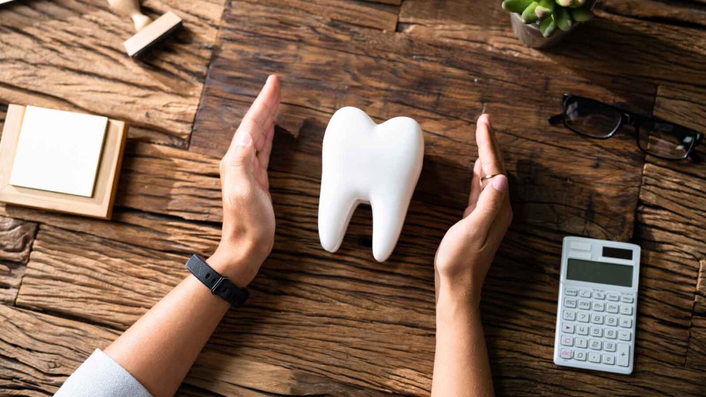 Hands protecting a model tooth.