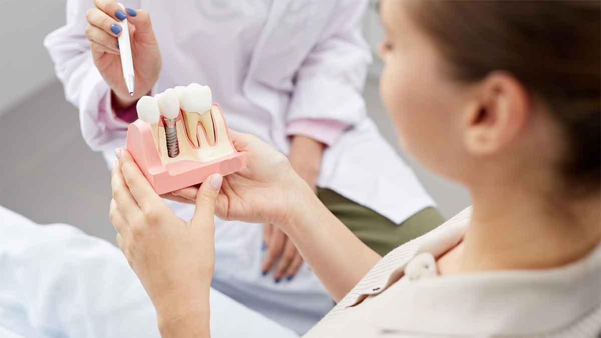 Patient holding a dental implant model during consultation.