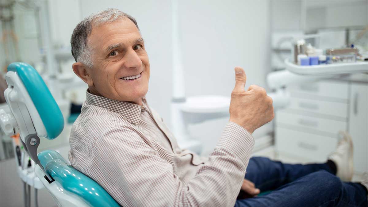 A senior man giving a thumbs-up after a successful dental visit.