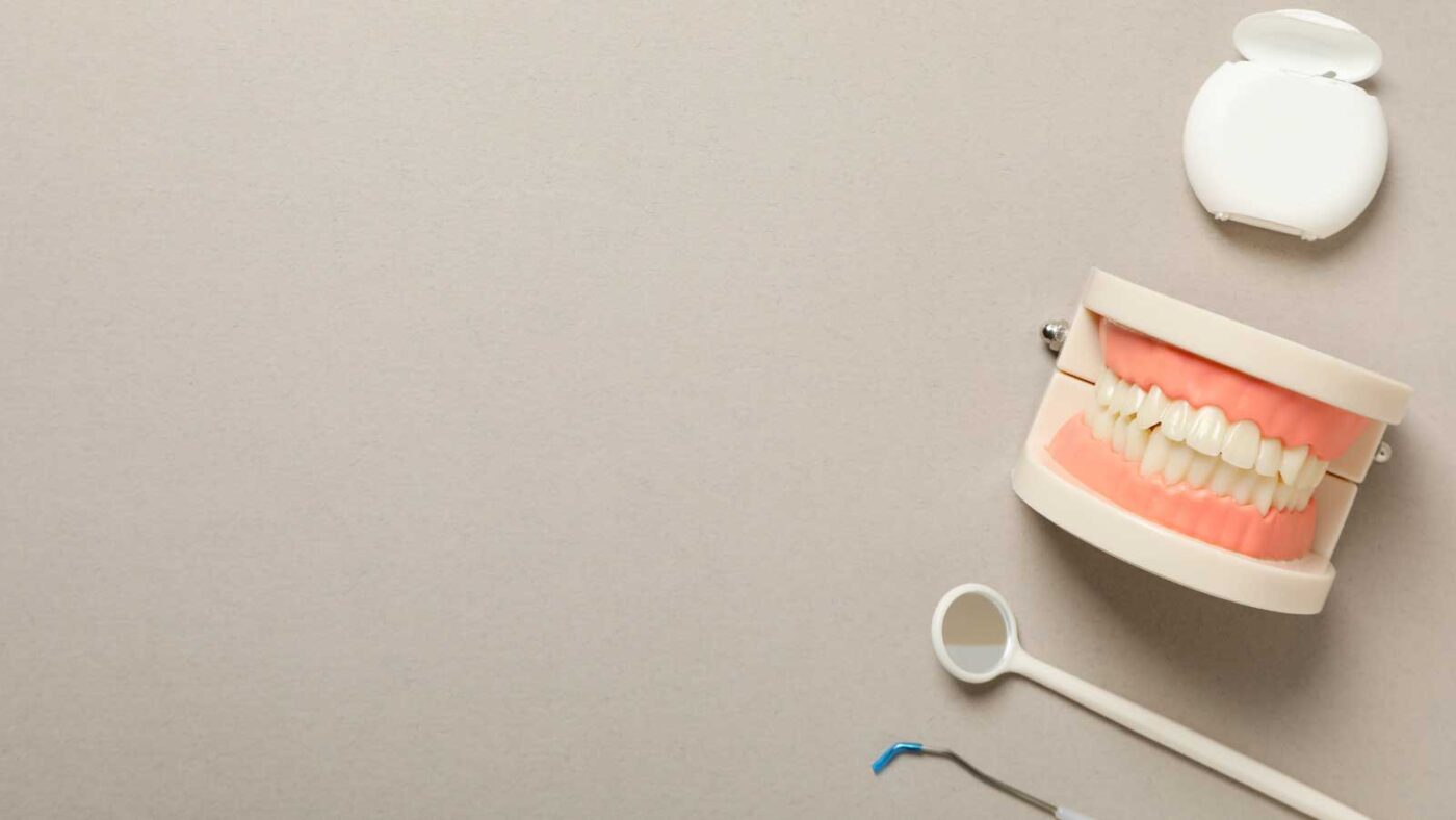 Dental model with tools and floss on a beige background.
