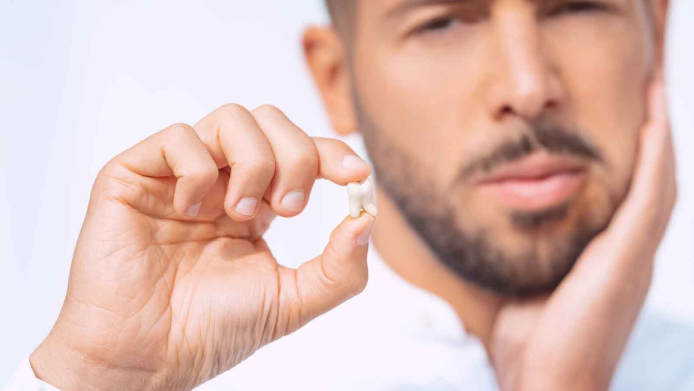 Man holding extracted tooth.