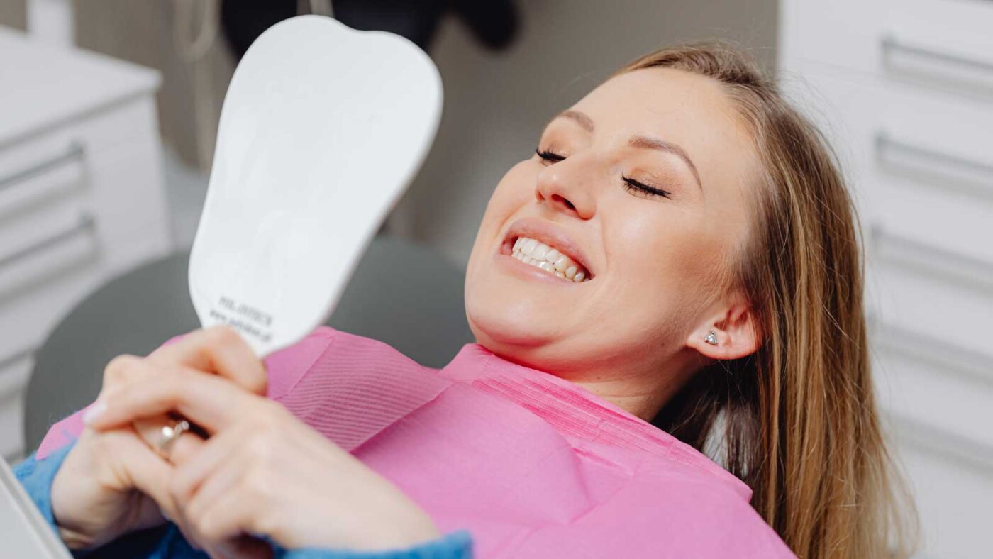 A woman smiles while checking her teeth